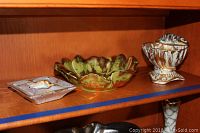Three Stangl ceramic decor pieces on a wooden shelf: square ashtray, green decorative bowl, small ornate vase/bowl.