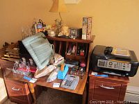 Wide view showing Kodak printer on small filing cabinet, office desk with assorted office supplies, small dark wood furniture pieces, and decorative items.