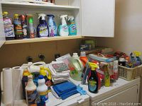 Cleaning supplies and laundry detergents arranged on a laundry surface with paper towels and cloths