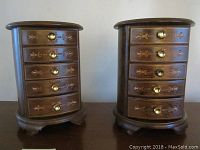 Front view of two matching wooden jewelry boxes with decorative inlay and brass knobs on drawers.