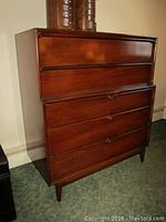 Front view showing five drawers with integrated curved wooden handles and the rich wood finish.