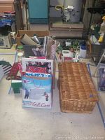 Photo of wicker trunk, box, and bags containing Christmas linens and gift wrapping supplies in a basement or workshop area.