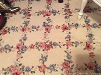 Close view of floral pattern with pink, red, and blue flowers on cream background showing some stains and wear.