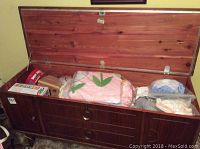 Open cedar chest showing interior with blankets and games inside, wooden construction with cedar wood interior, and dark stained exterior surface.