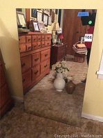 Rectangular wall mirror showing the reflection of a room and furniture, with visible wear at the bottom edge.