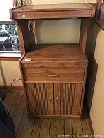 Front view of wooden storage cabinet showing drawer and two-door cabinet base with brass handles.
