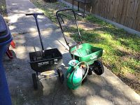 Overall photo showing three garden tools on pavement: Turf Builder fertilizer spreader, insect sprayer, True Temper fertilizer spreader