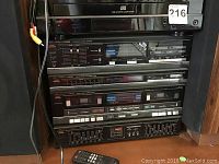 Stacked audio components: Insignia DVD player on top, followed by Fisher system with tuner, cassette decks, and graphic equalizer.