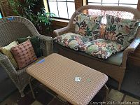 Full set photo showing wicker style love seat, chair, and table with cushions.