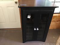Front view of black wooden wine cabinet with glass doors, showing overall structure and door design.