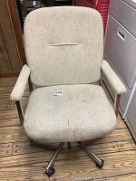 Front view of beige fabric office chair with padded seat and backrest, metal base with wheels.