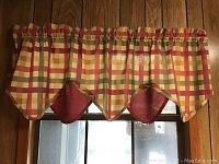 Plaid valance curtain in red, cream, and yellow hanging on window