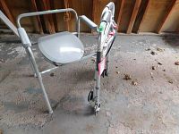 4-wheel walker with seat and padded armrests photographed in a garage setting on a rough floor, showing overall condition and design details