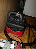 Photo of Craftsman 1.6 gallon wet dry vacuum showing handle, body, and hose on parquet floor near wall.
