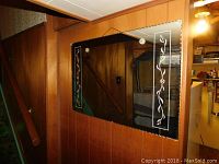 Hall mirror mounted on wall showing scalloped edges and floral etchings