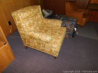 Full side view of vintage armchair showing floral upholstery and wooden legs.