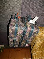 Side view of two floral fabric Carroll Reed suitcases stacked, showing straps and locks with no keys.