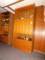 Full view of the tall mid-century modern faux wood cabinet with closed doors, showing the wood grain finish and knob hardware.