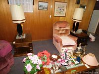 Two medium brown wood side tables with drawer placed in a wood-paneled basement room beside chairs, showing overall appearance and condition.