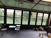 Wide view showing several furniture pieces including tables and plant stands, along with some pots and flowers gathered together in corner