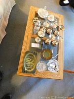 Overview of all items on wooden tray showing 6 silver plated goblets, clear glass covered candy dish, 2 glass ashtrays, small gold bowl, silver small items, and ceramic ashtray with scene