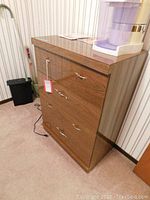 Front and side view of the wood dresser showing four drawers and metal handles.