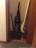 Sentron upright vacuum cleaner and additional cleaning tools stored in corner