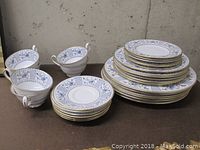 Overall view of the set showing three stacks of plates by size and four footed cups placed at front.