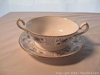 Single double handled bowl with liner plate showing Mandarin Blue floral and lattice pattern and gold accents