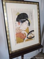 Framed lithograph of Japanese geisha looking into a mirror, showing the full frame and artwork.