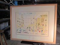 Full view of framed watercolor showing Italian village scene with blond wood frame and white mat