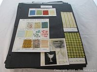Photo of scrapbook pages showing various vintage fabric samples and textile types mounted on black paper with typed labels and handwritten notes.