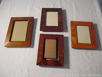 Four wooden picture frames laid out on cloth background, showing different sizes and wood finishes