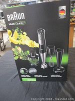 Photo of the front of the boxed Braun Multi Quick 7 hand blender showing the product and included accessories on the box graphic.