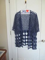 Navy blue crocheted open-knit short sleeve top hung on door showing cut-out stitch pattern