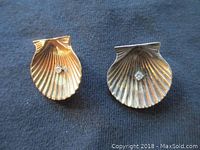 Front view of gold seashell clip-on earrings showing diamond chips and shell ribbing detail.