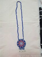 Full view of blue beaded necklace with round pendant showing overall length and shape.