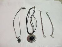 Full view of two necklaces and two bracelets laid flat on white background.