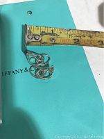 Pair of sterling silver clip earrings with tape measure showing length just under 1 inch on Tiffany blue background.