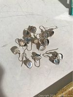 Seven pairs of sterling silver heart-shaped dangle earrings laid out on a white surface showing overall lot condition and quantity.