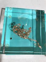 Top view of the gold chain lying loosely coiled on a transparent blue surface.