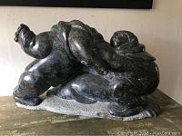 Front-side view of large dark soapstone carved Inuit figure sculpture showing details and natural stone texture.