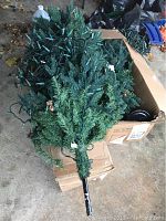 Top view of first four-foot pre-lit artificial Hyde Park stake Christmas tree showing green branch tips, black stake base, and attached Christmas string lights.
