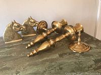 Pair of brass horse head bookends and two brass carriage lights displayed on a textured surface.