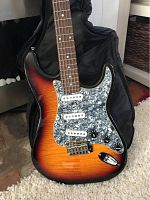 Close-up of front body showing sunburst finish, 3 white single-coil pickups, 5 control knobs, and pearloid pickguard.