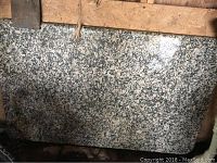 Speckled granite slab leaning against framing, shows full surface pattern and dimensions