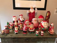 Wide shot showing full collection of Santa-themed figurines and decorative items arrayed on a table.