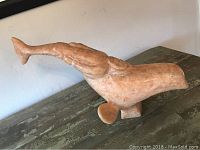 Side view of the soapstone whale sculpture showing its overall shape and tail fin damage.