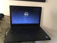 Front view showing the Dell laptop powered on at the Dell logo screen.