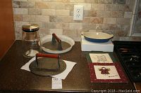 Photo showing the entire lot on a kitchen counter including two cast iron bacon presses, Teavana jar, Le Creuset dish, cookie sheet, hot pads, and utensils.